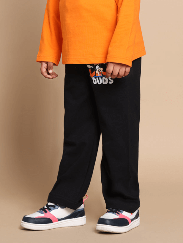 Child wearing orange-black unisex Goofy co-ord set with elastic waistband, joggers, and colorful sneakers.