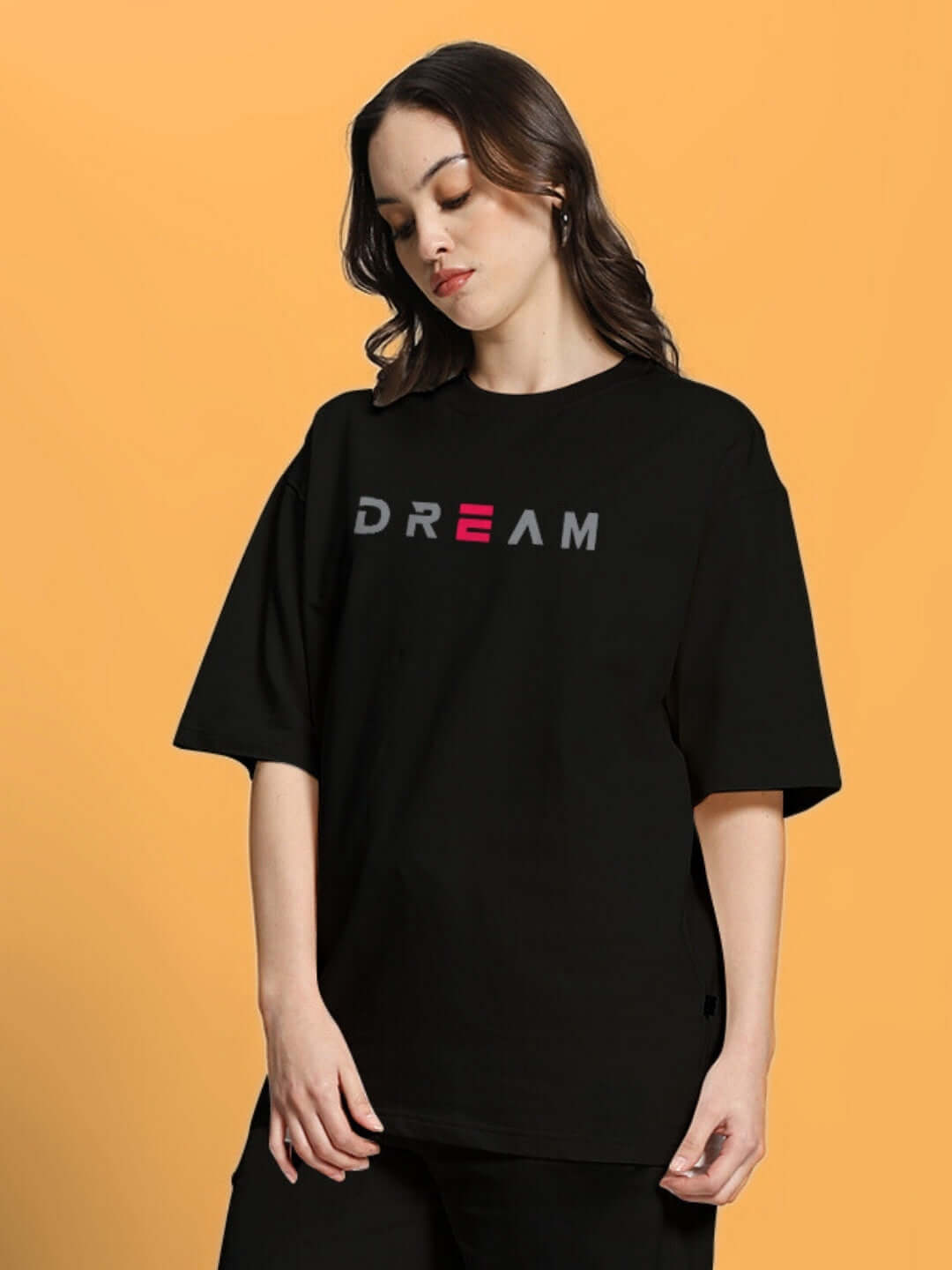 Woman wearing black oversized t-shirt with 'Dream' print, made of premium heavy gauge cotton blend, 240 GSM, by Color By Colours.