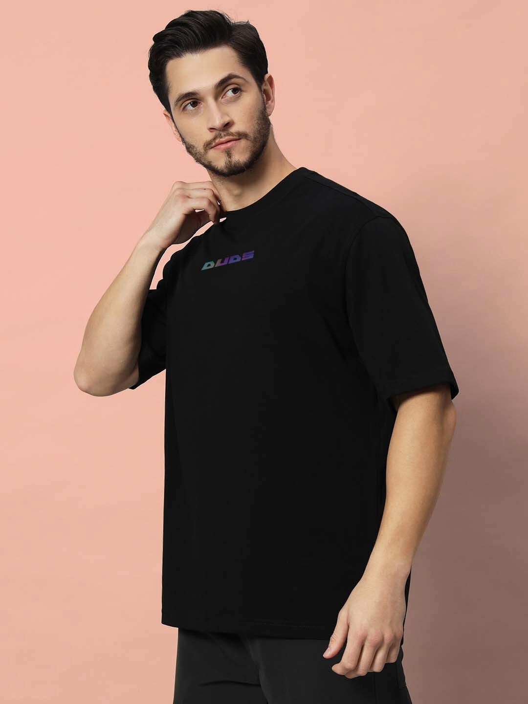 Model wearing GOHAN OVER-SIZED T-SHIRT OFF WHITE in black, casual streetwear style against a peach background.