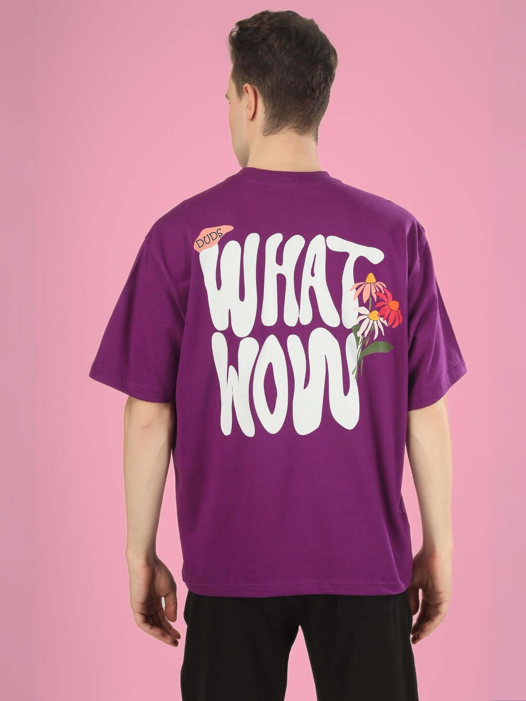 Back view of WHAT WOW OVER-SIZED PRINTED T-SHIRT PURPLE with bold lettering and floral design on model.