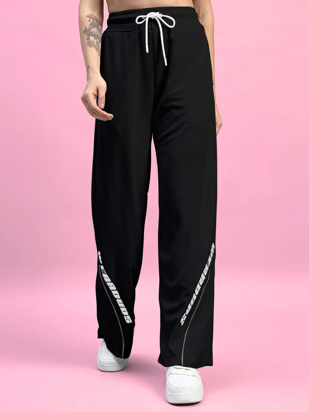 Model wearing black women's relaxed fit baggy joggers with white drawstring, showcased against a pink background.