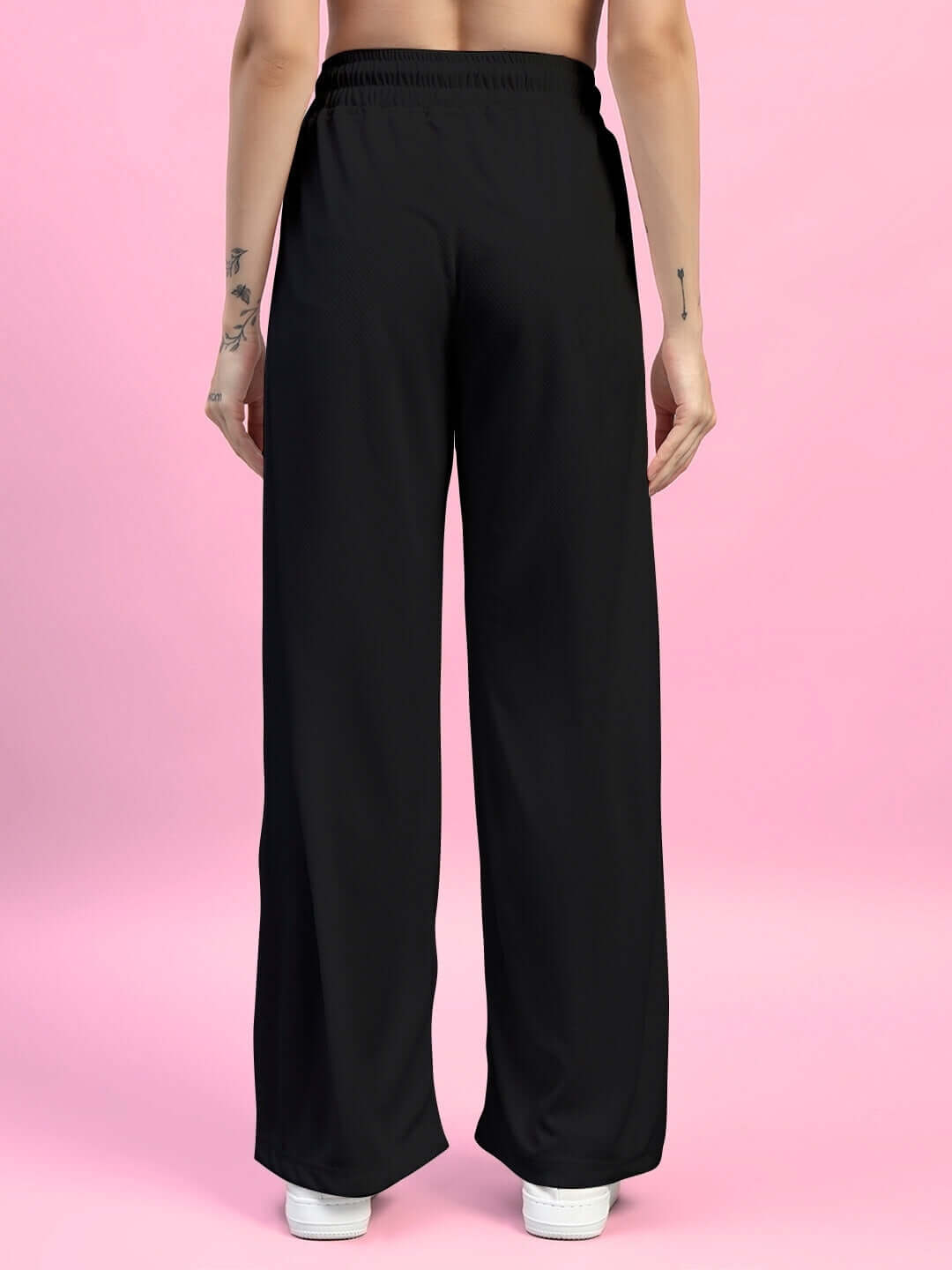 Back view of Women's Cubby Relaxed Fit Baggy Joggers in black against a pink background.