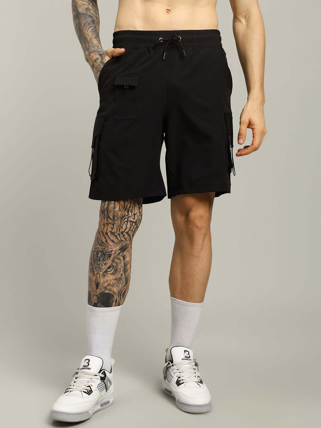Man wearing VEGA Cargo Shorts in black, showcasing pockets and relaxed fit. Ideal for custom sizing options. Urban casual style.