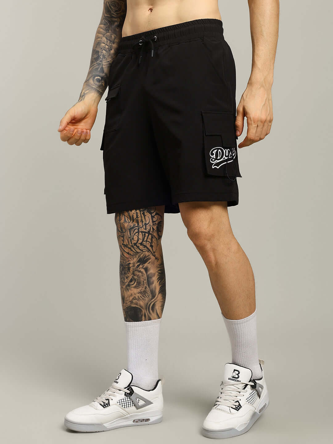 Man wearing VEGA CARGO SHORTS in black with side pockets, showcasing casual summer style.