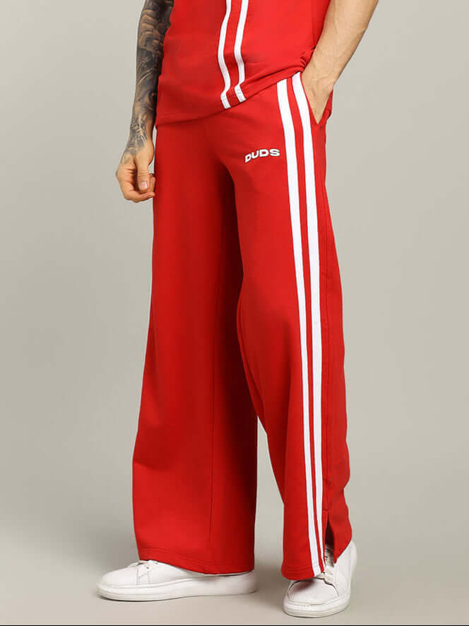 Red joggers with white stripes from DUDS, featuring custom fit options and tailored craftsmanship, modeled with matching attire.