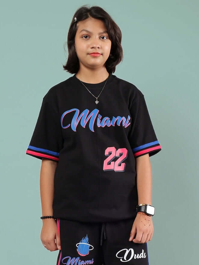 Child wearing a black Miami oversized t-shirt featuring colorful text and number, suitable for boys and girls by DUDS.