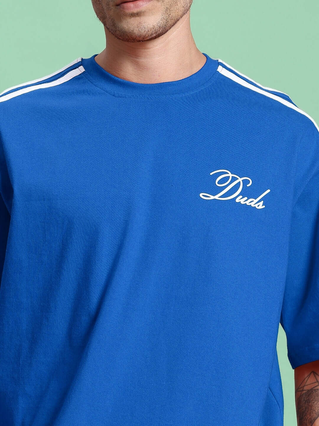 Blue over-sized t-shirt made from premium cotton fabric, featuring white text detail and stripe design on shoulders.