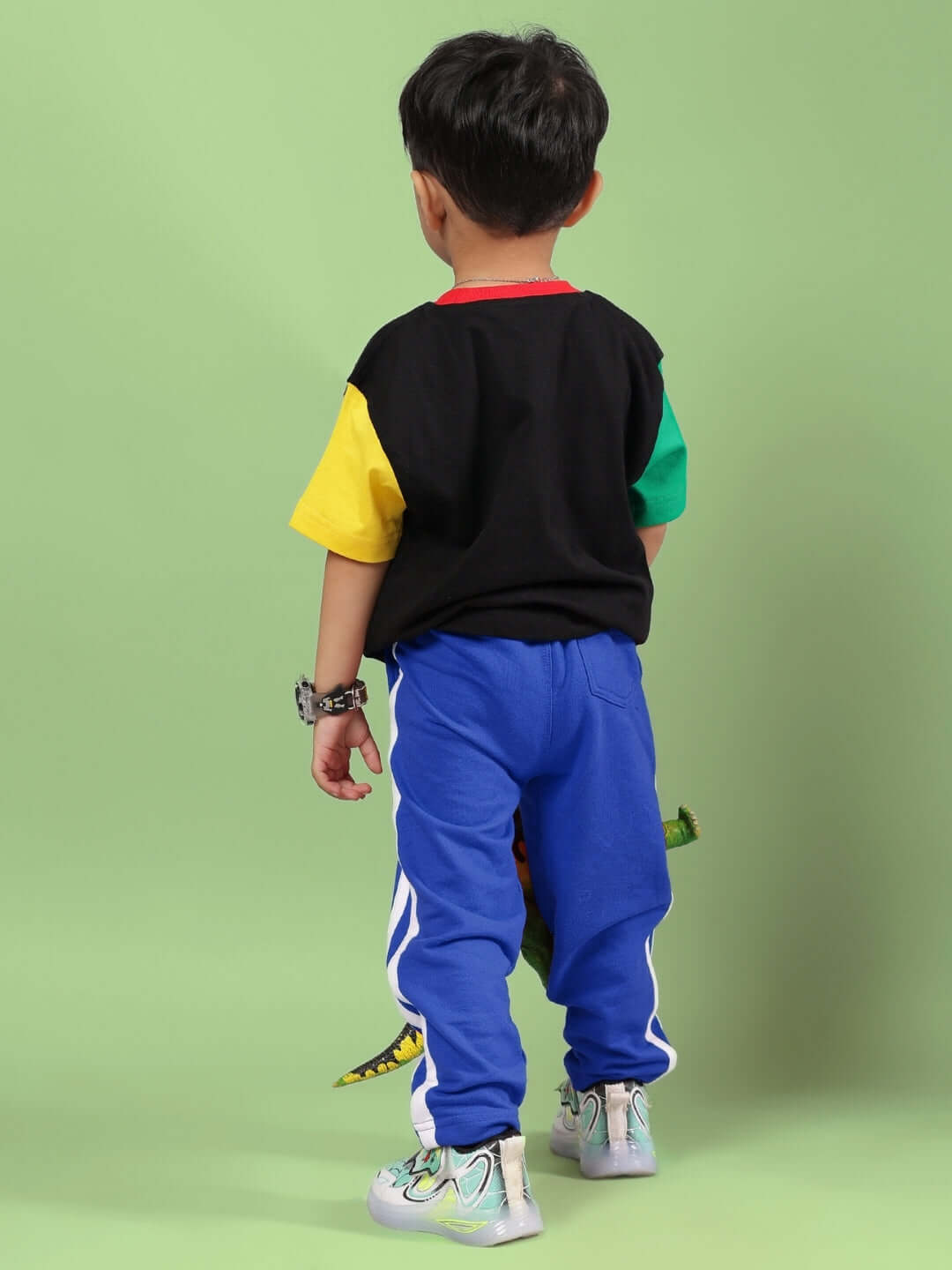Child wearing a colorful puppy dog printed co-ord set for boys and girls, featuring a black and blue design, standing against a green background.