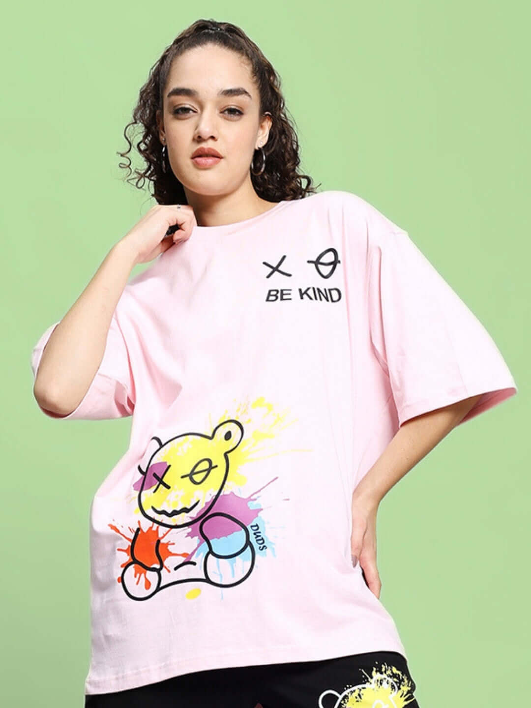 Model wearing pink oversized 'Be Kind' t-shirt with colorful graphic design, crafted from premium heavy gauge cotton fabric.
