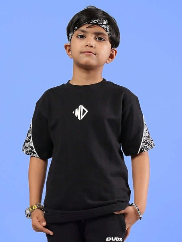 Young child wearing a black Calvin oversized t-shirt with bandana sleeves, designed by DUDS.