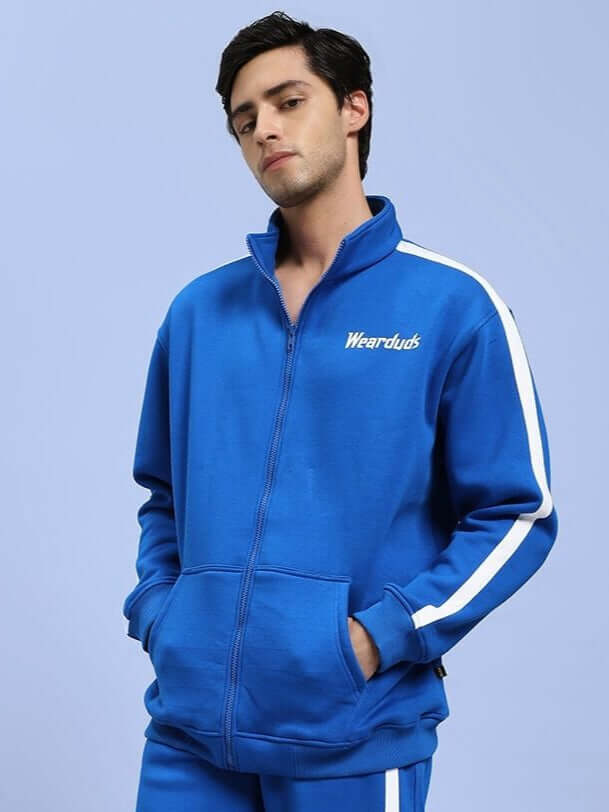Man wearing RAPID STRIDE COTTON FLEECE JACKET ROYAL BLUE, featuring zip-up front and pockets, ideal for outdoor activities and training.