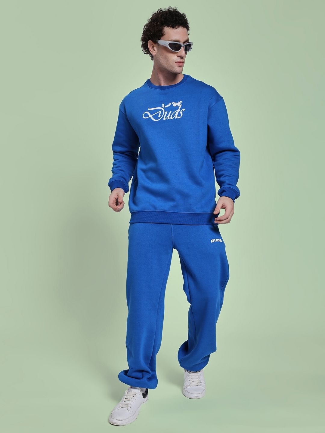 Man wearing NATURE LINK FLEECE CO-ORD SET ROYAL BLUE, featuring a blue sweatshirt and joggers, styled in a relaxed pose.