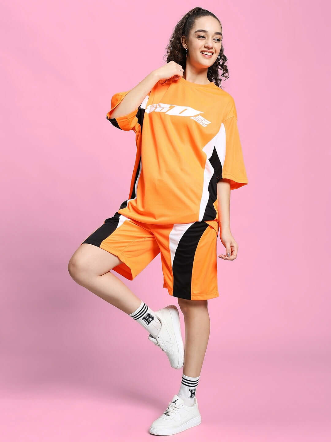Model wearing Women's FIFA Colorblock Co-ord Set in orange, made from sports polyester fabric, on a pink background.