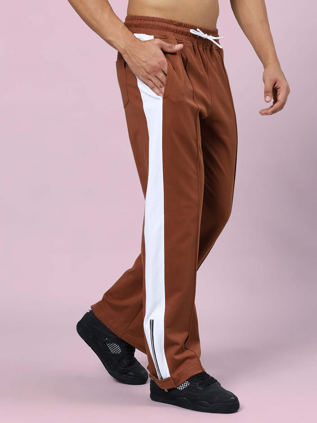 Man wearing brown Wonder Slit Zipper Joggers with white stripe, showcasing comfortable fit and design by DUDS.