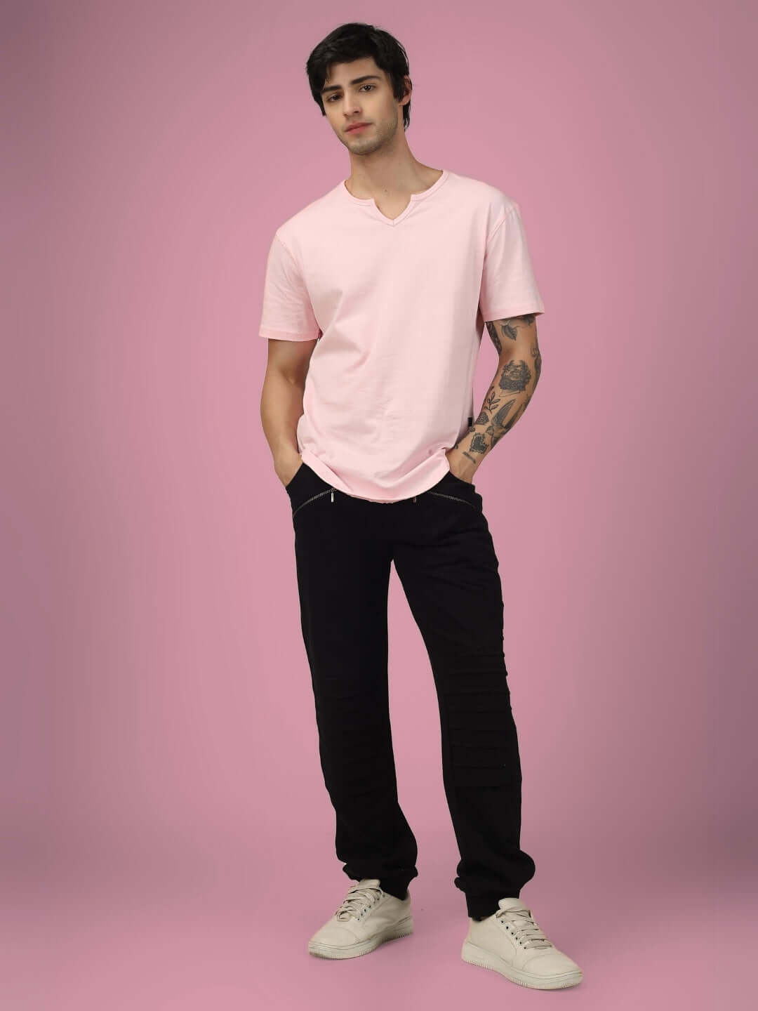 Man wearing pink shirt and 2 ZIPPER POCKET COTTON JOGGER BLACK against pink background. Stylish jogger pants for casual wear.