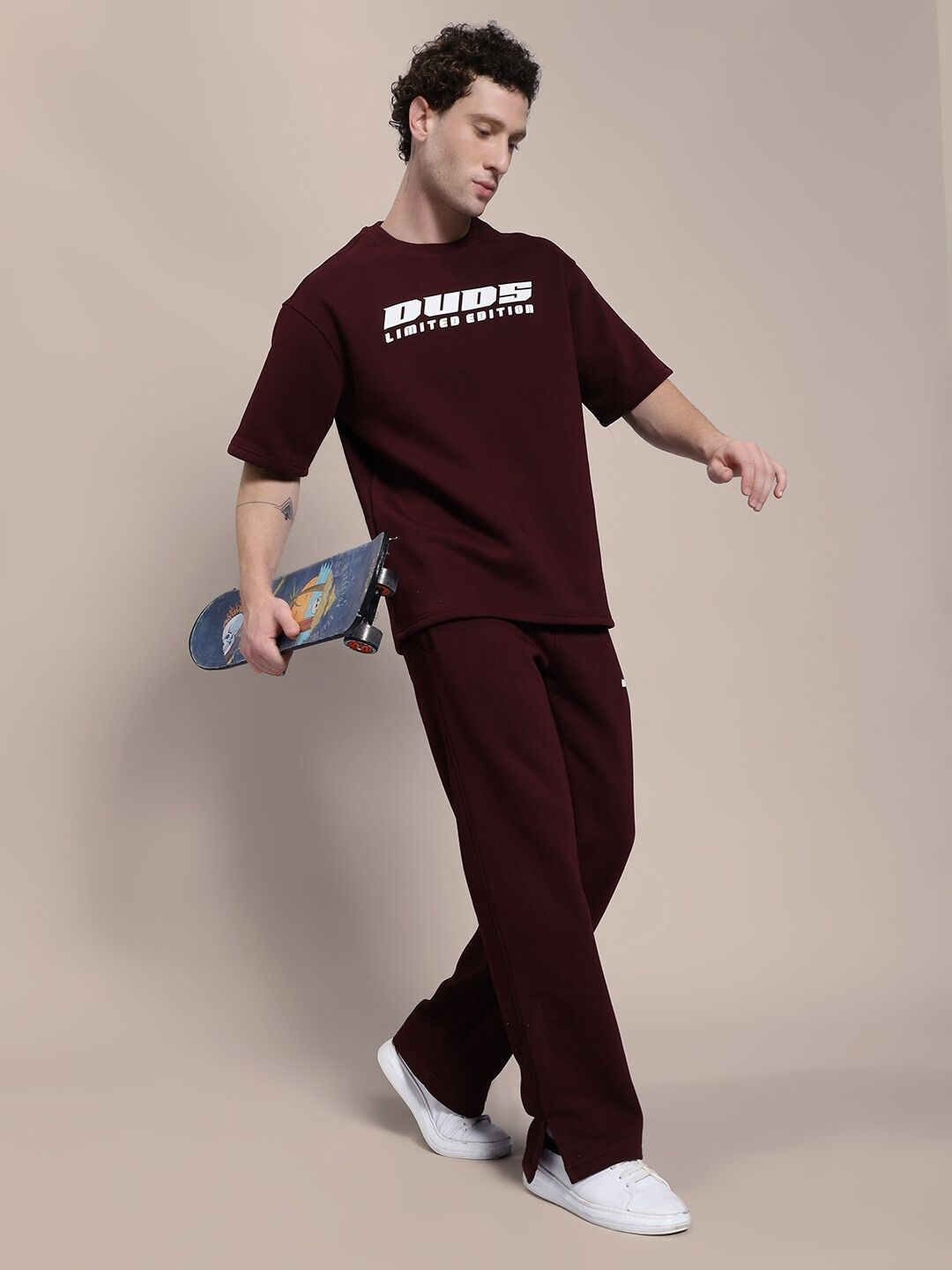 Person wearing SKODA FLEECE CO-ORD SET MAROON holding a skateboard, showcasing comfortable and stylish premium fleece outfit.