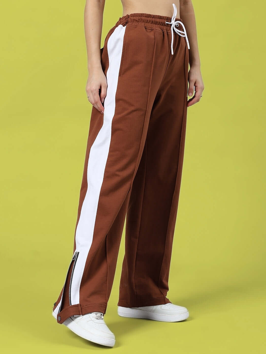 Model wearing brown women's wonder slit zipper joggers with white side stripes and ties, ideal for custom fit orders, made by DUDS.