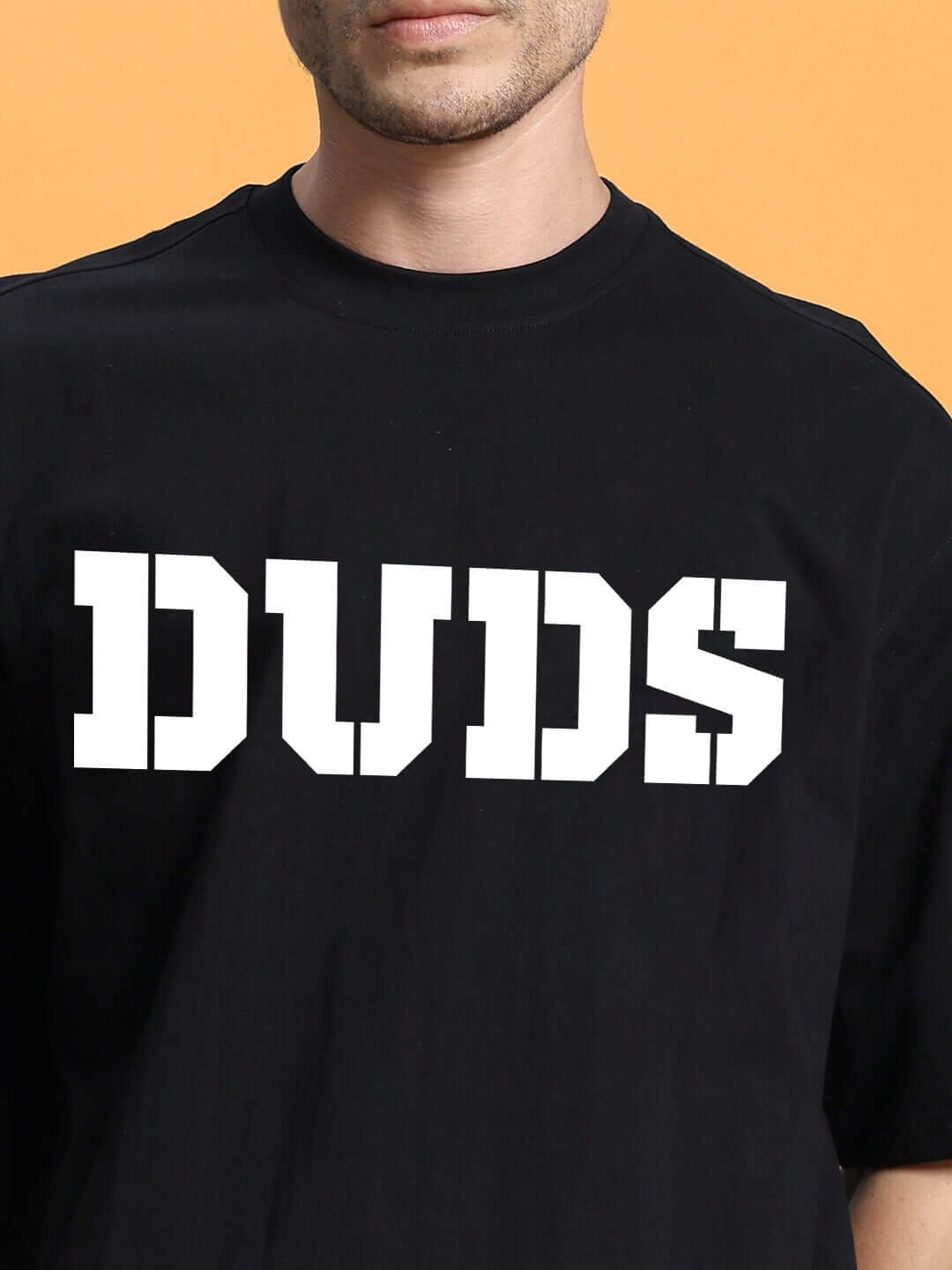 Black oversized t-shirt with 'DUDS' printed in bold white letters against an orange background.