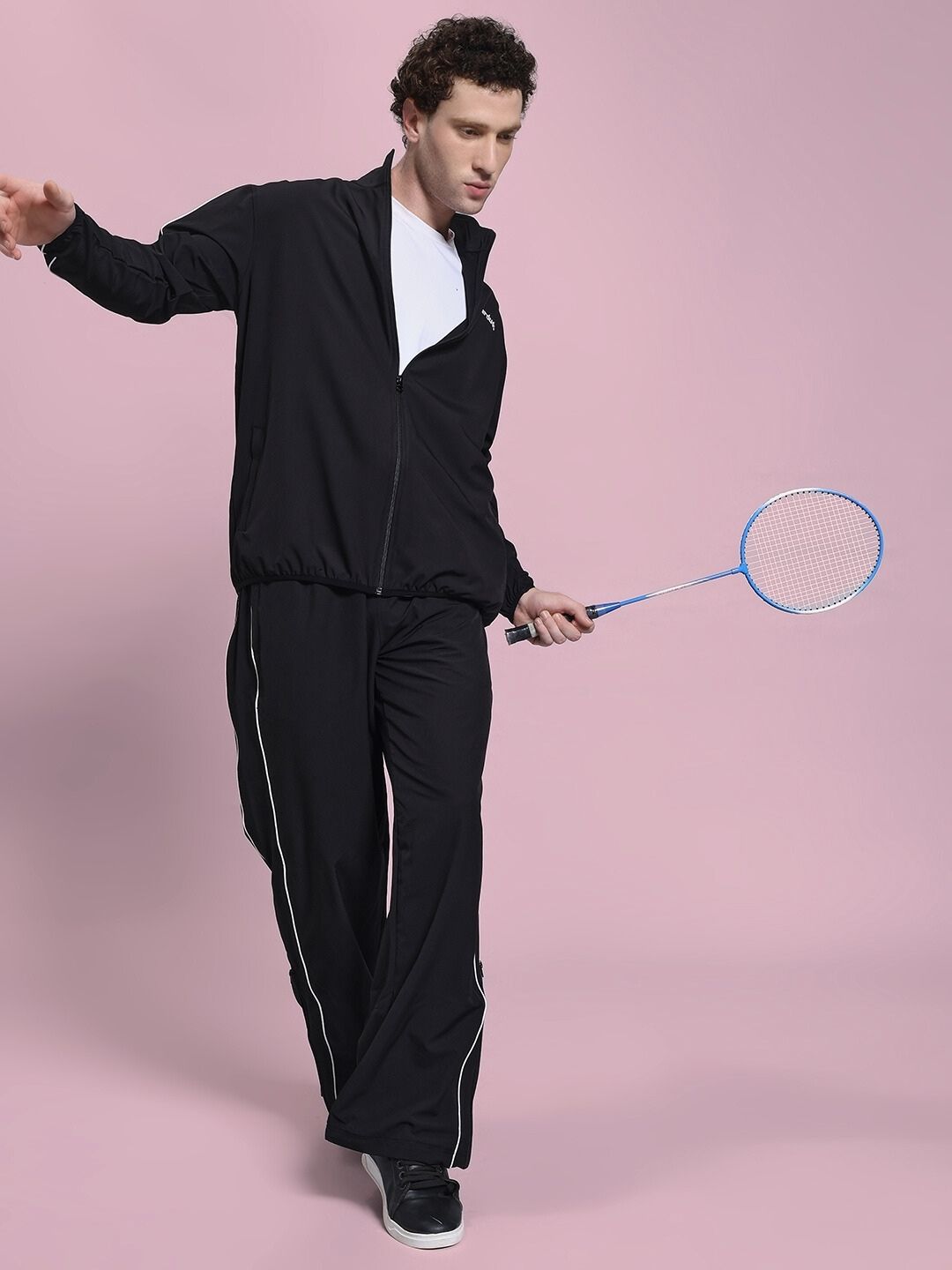 Man wearing RELIGHT RELAXED FIT CO-ORD SET BLACK with badminton racket on pink background.