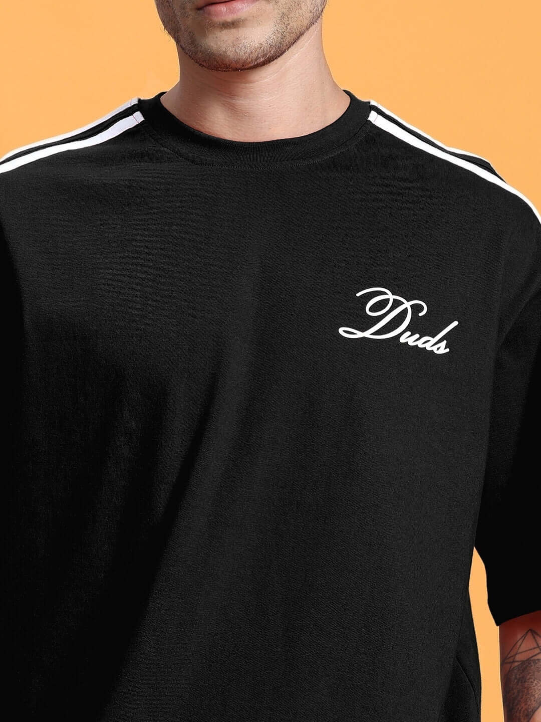 Model wearing SCOTIA oversized black T-shirt with white stripes and logo, made from premium cotton blend, by Color By Colours.