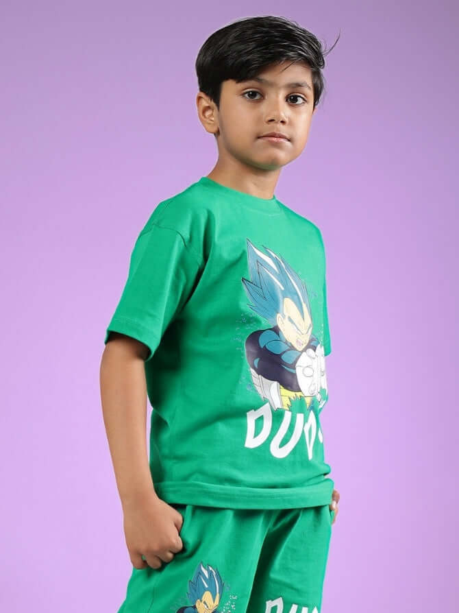 Boy wearing green SATORU graphic T-shirt and matching shorts for boys and girls by DUDS against purple background.