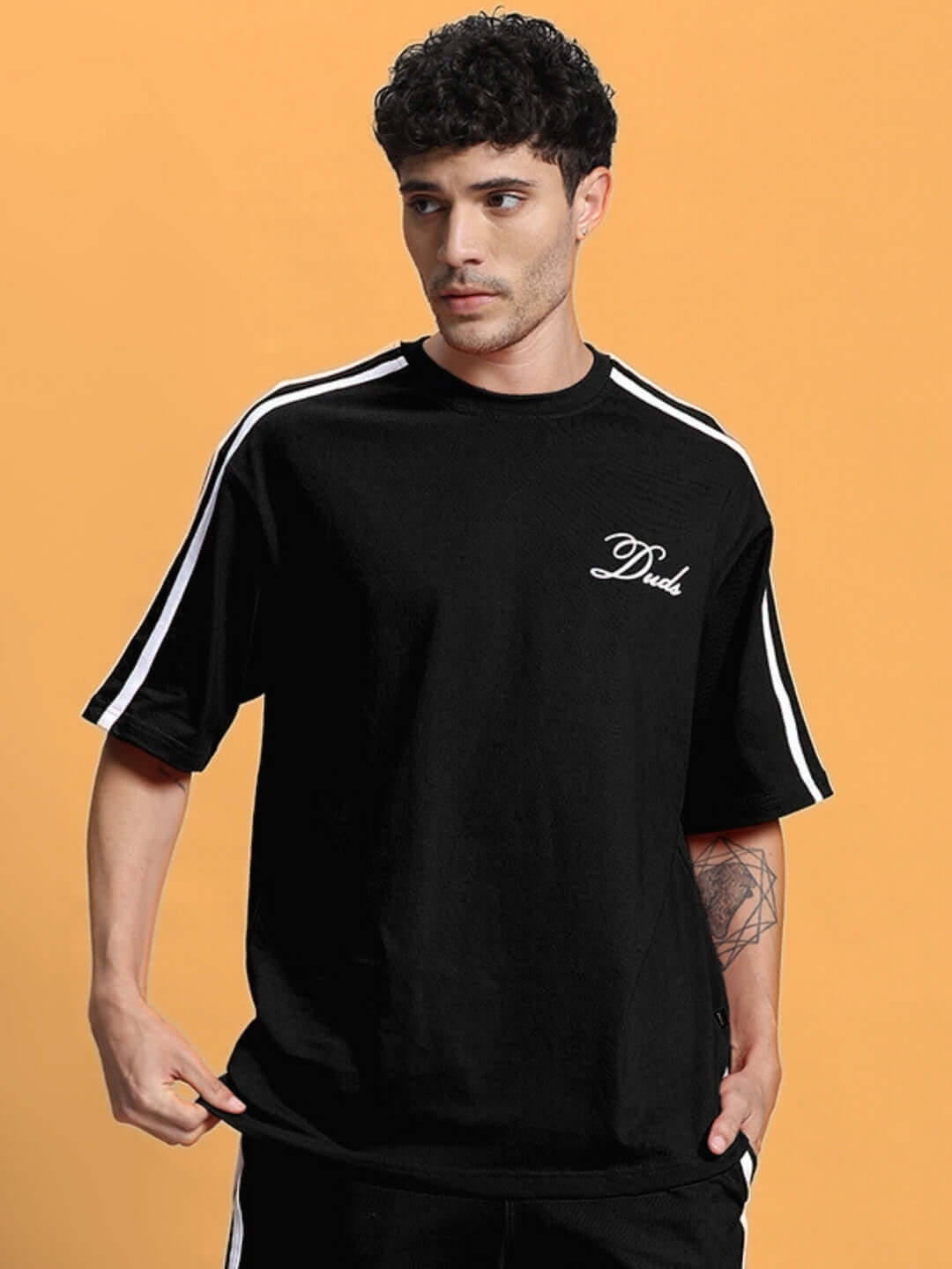 Model wearing SCOTIA over-sized black T-shirt with premium heavy gauge fabric, featuring striped sleeves and 'Dude' embroidery. Fashionable casual wear.