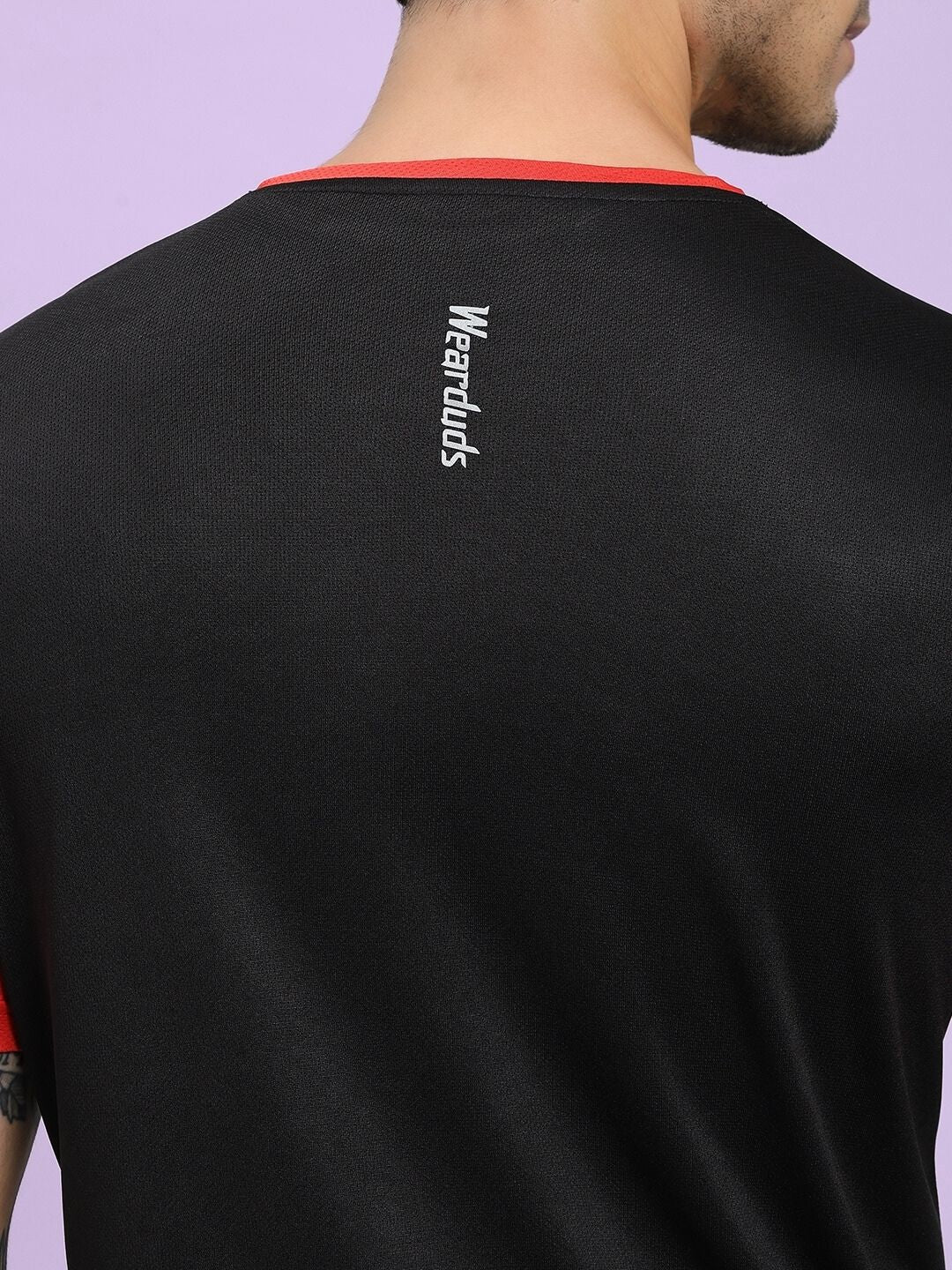 Black t-shirt with red collar and 'Wearduds' logo on the back against a light purple background