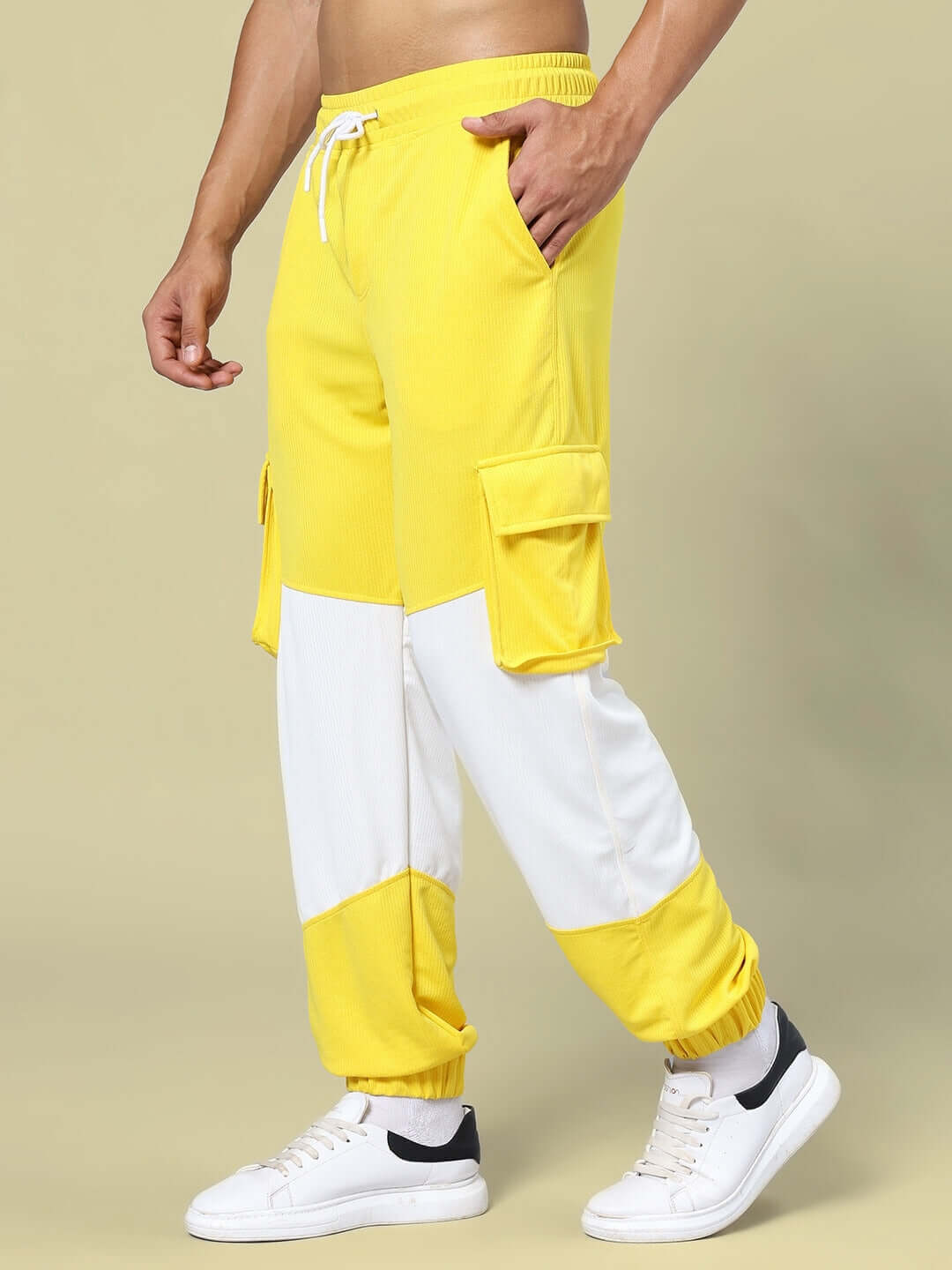 Man wearing yellow and white relaxed fit joggers with cargo pockets, paired with white sneakers, showcasing DUDS apparel.