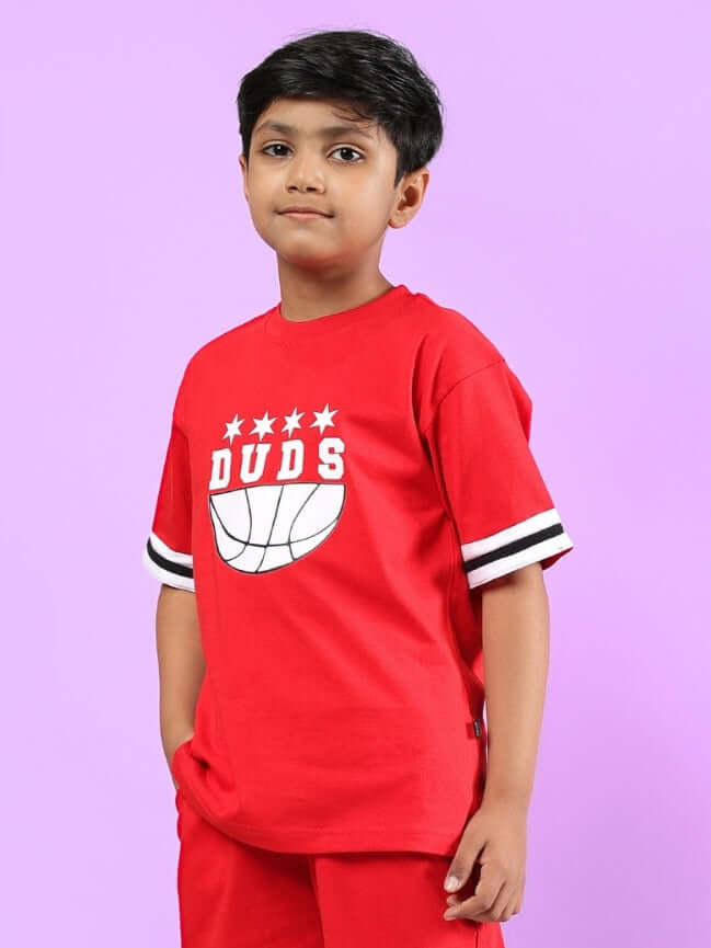 Child wearing red DIGGIN oversized t-shirt for boys and girls by DUDS, featuring a basketball graphic and white striped sleeves.