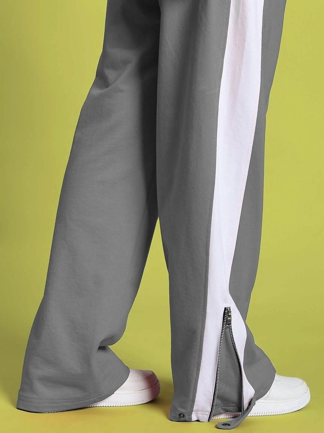Women's grey-white joggers with zipper detail, showcasing style and comfort on a green background.