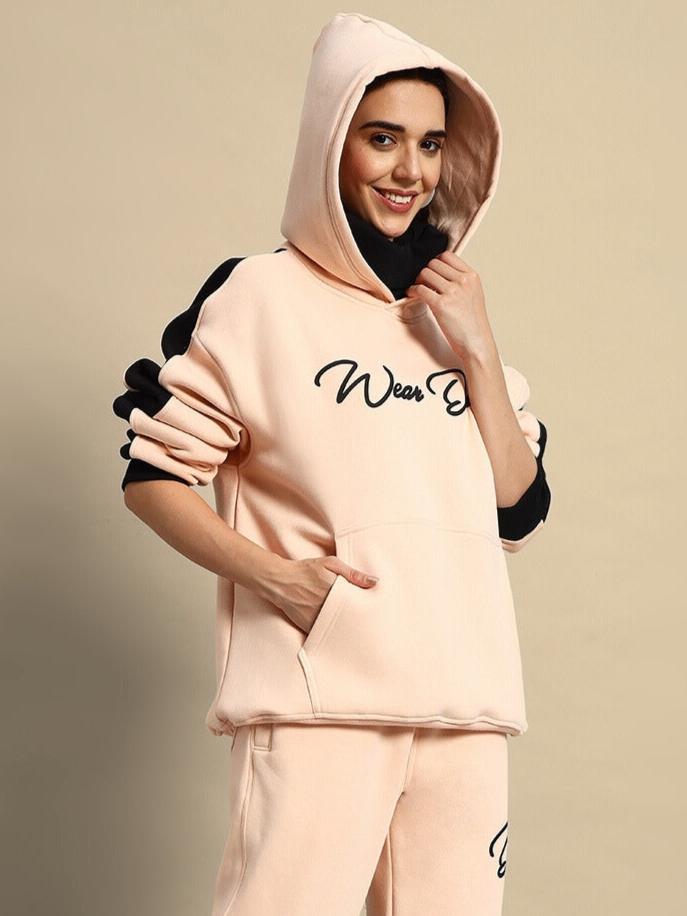 Woman wearing beige-black regiment fleece hoodie with hood up, stylish and comfortable outfit for casual wear.