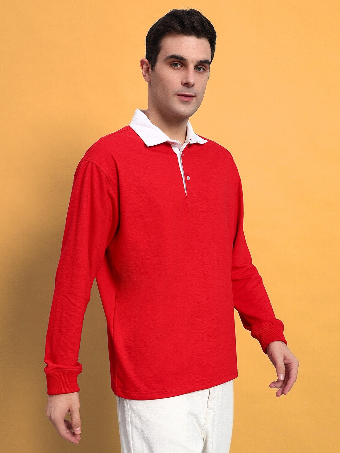 Model wearing SAGOL red oversized polo sweatshirt in premium cotton blend, showcasing long sleeves and relaxed fit against a yellow backdrop.