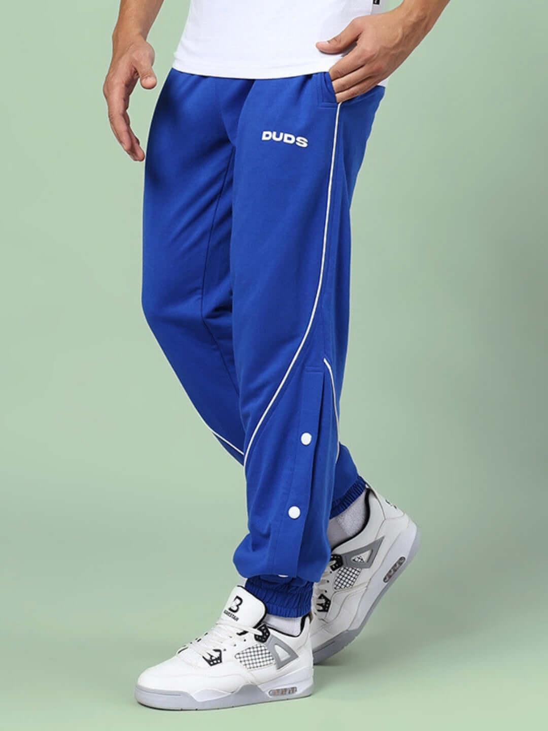 Man wearing BROSSFINE Contrast Joggers in Royal Blue, featuring white piping and button detail, styled with sneakers by DUDS.