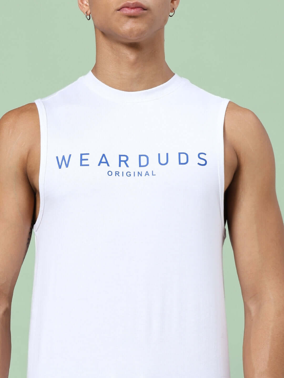 Model wearing a white sleeveless top with 'WEARDUDS ORIGINAL' printed in blue, against a light green background.