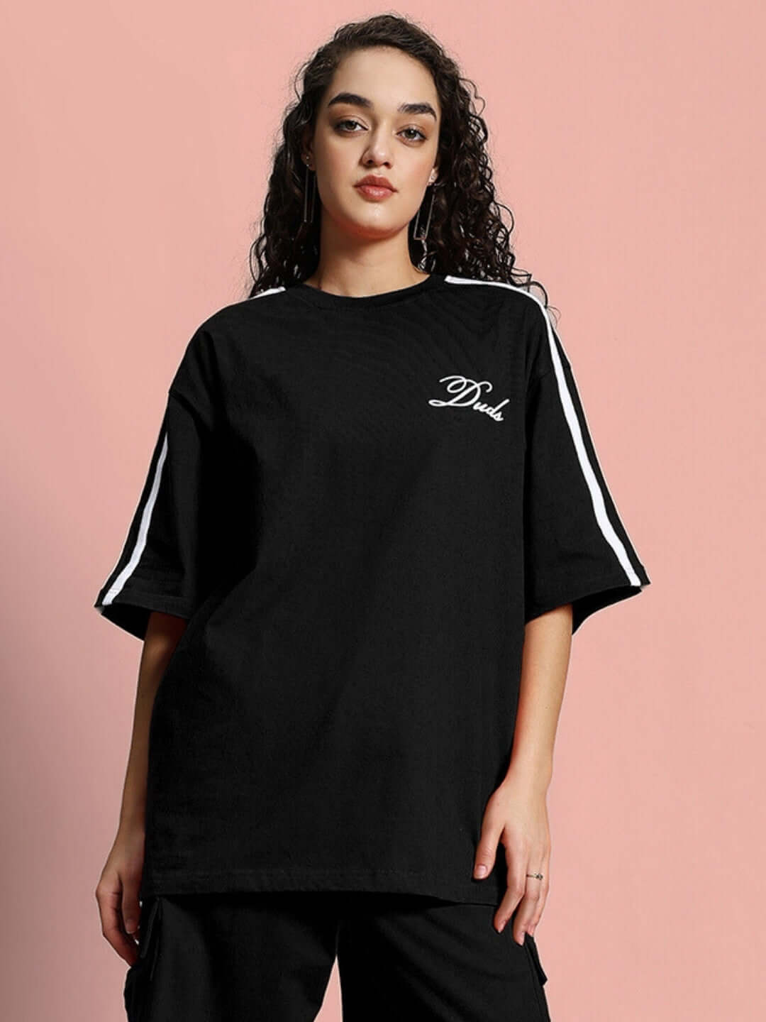 Woman wearing black oversized t-shirt with stripes, made from premium cotton blend. Stylish casual look.