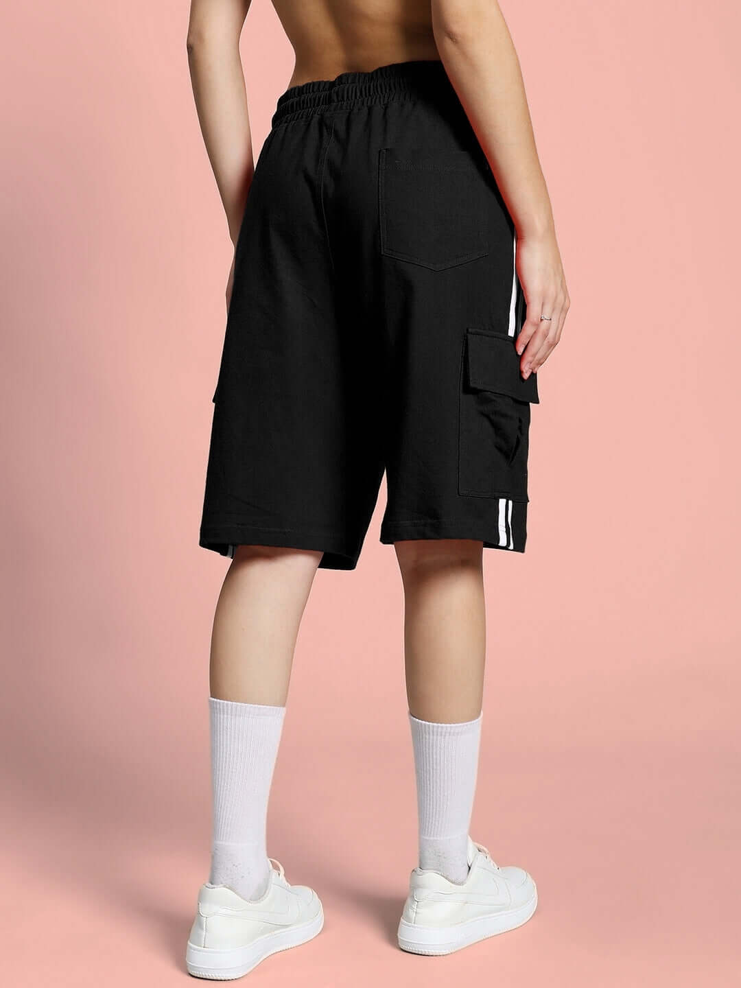 Back view of women's black Scotia regular fit shorts with elastic waistband, worn by model against pink background.