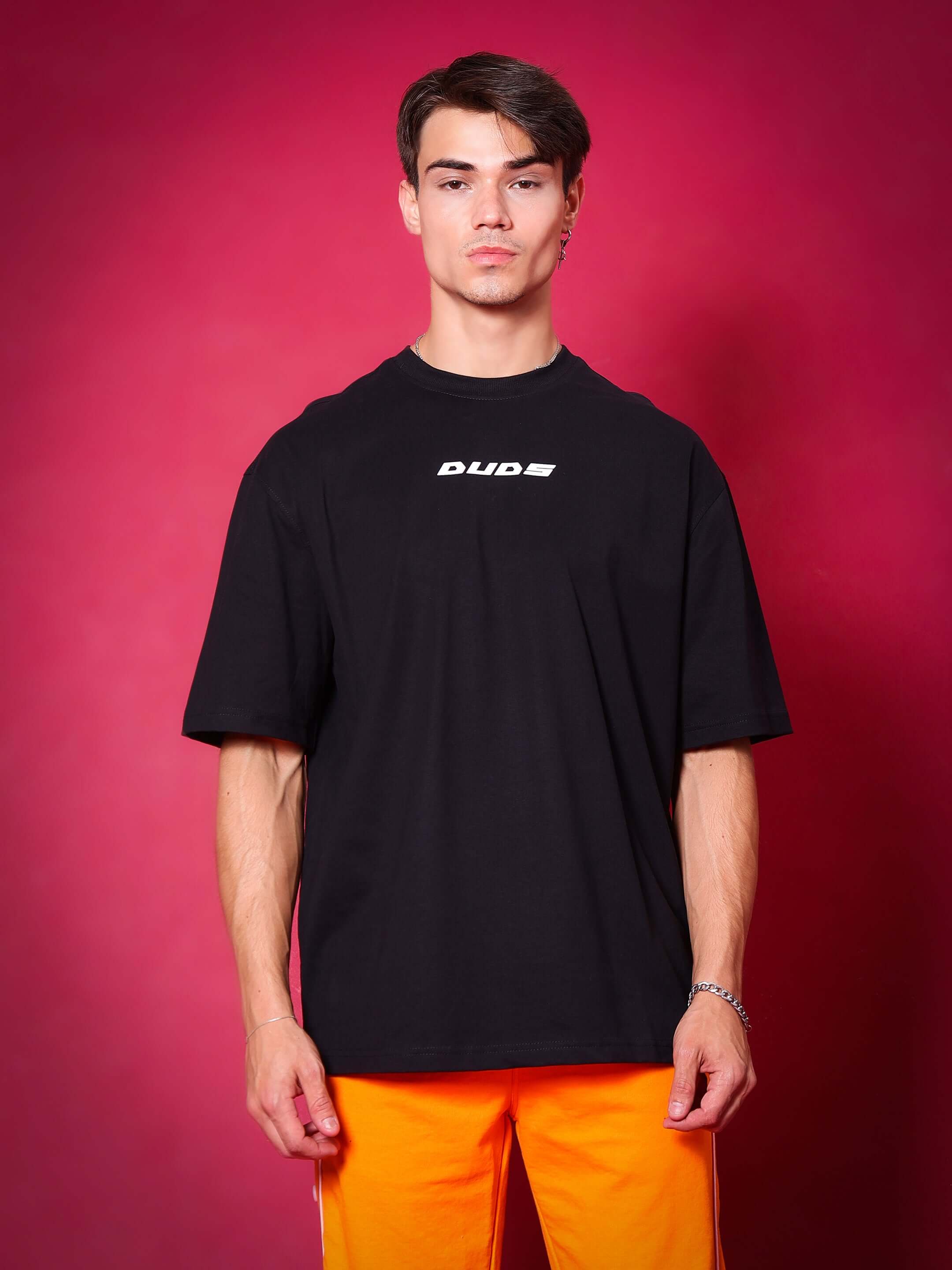 Model wearing GLITTERED HD MOON OVER-SIZED T-SHIRT BLACK against red background, showcasing streetwear fashion by WEAR DUDS.