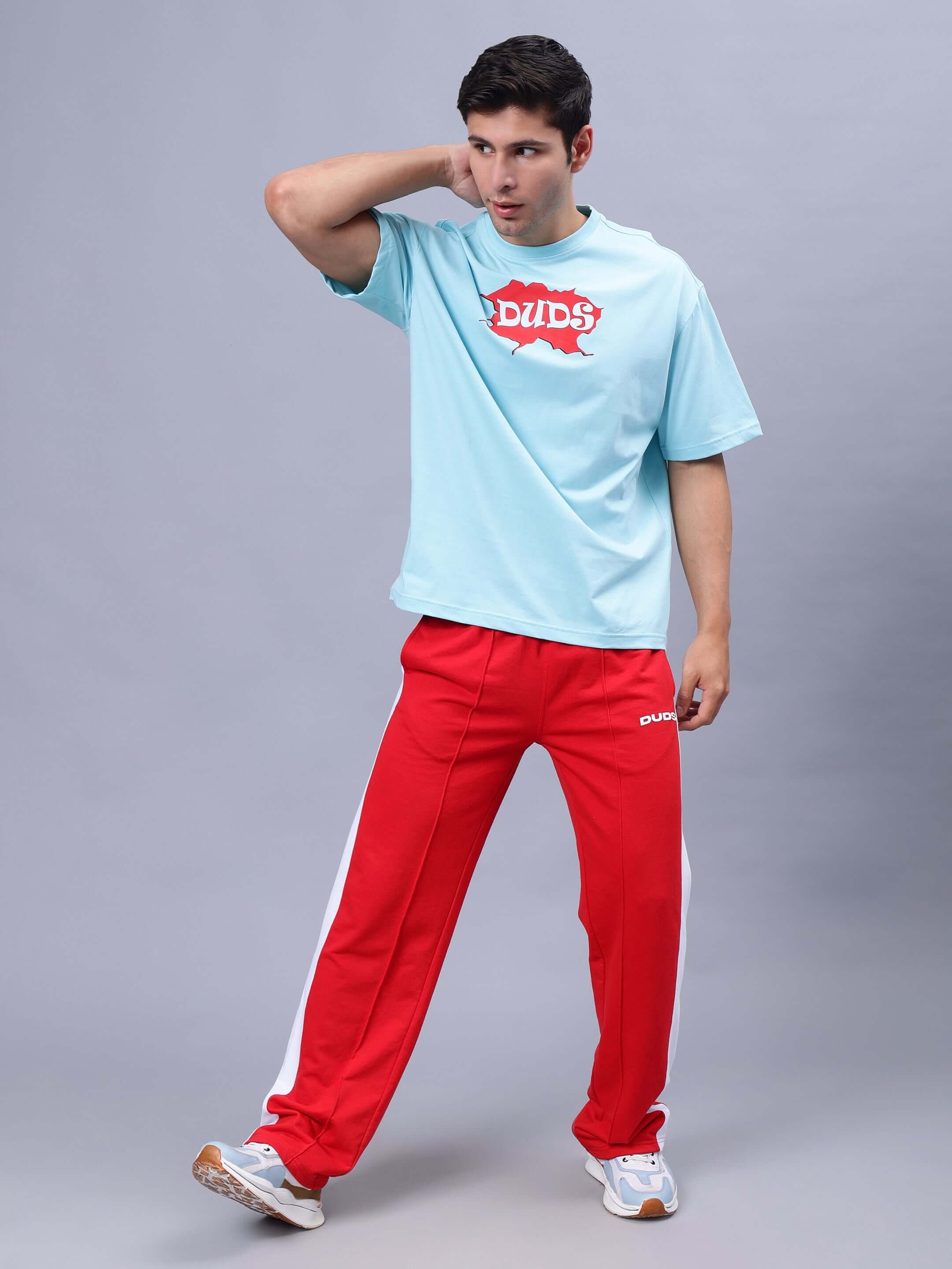 Man wearing RADIO OVER-SIZED T-SHIRT SKY BLUE paired with red track pants.