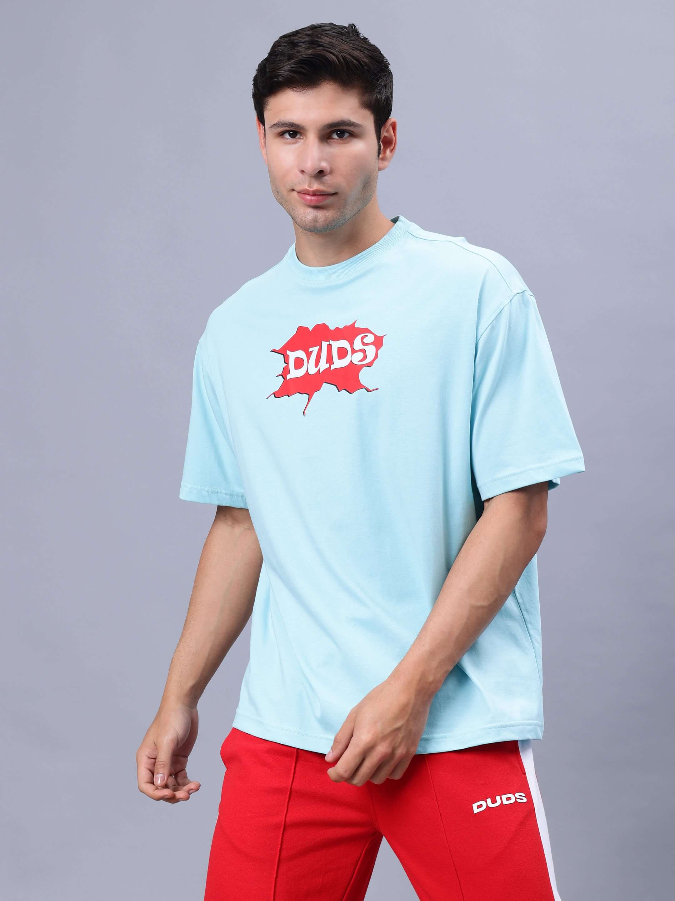 Model wearing RADIO OVER-SIZED T-SHIRT SKY BLUE with red DUDS logo.