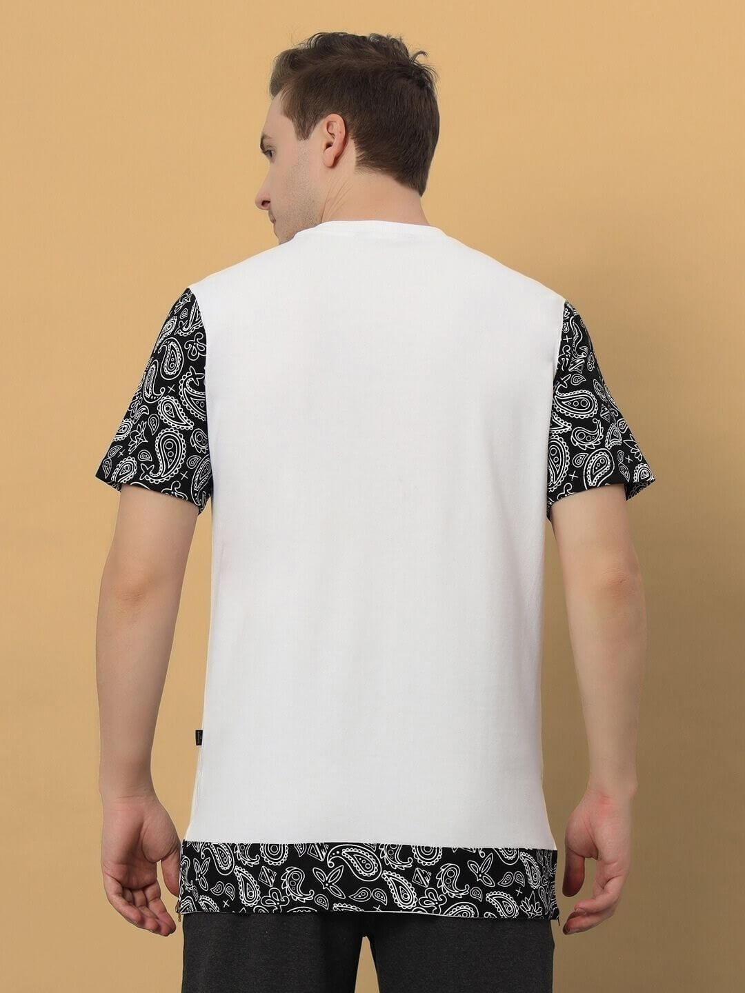 Back view of a man wearing a white oversized Beasley T-shirt with black paisley patterned sleeves, made from premium cotton blend fabric.