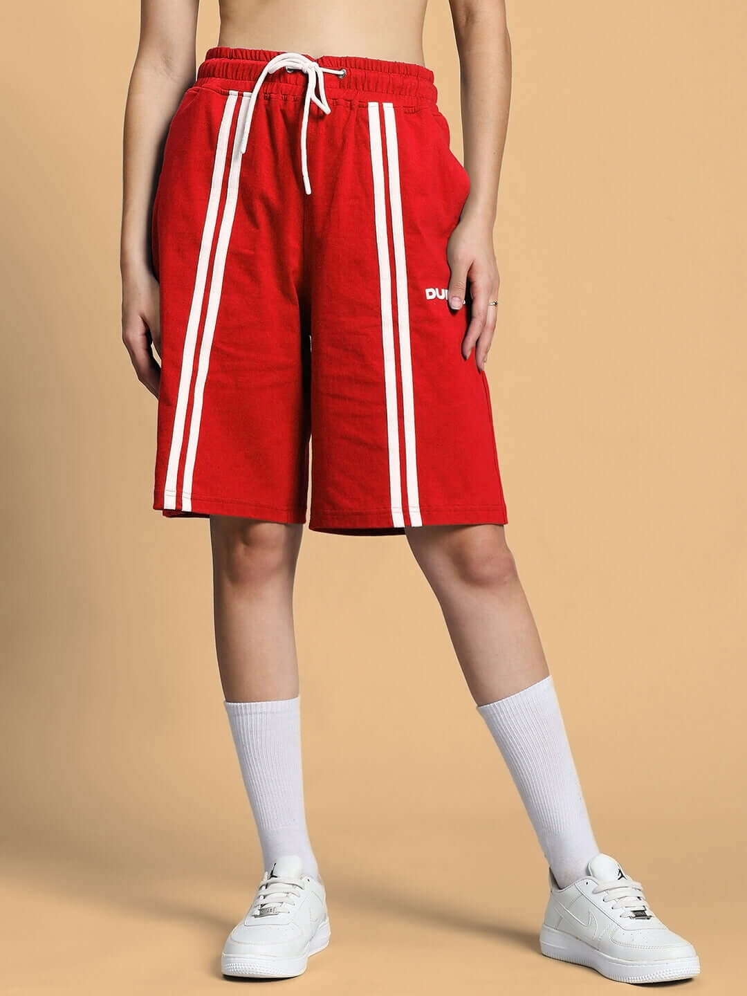 Women's red shorts with white stripes, regular fit, available with custom fit option from DUDS, styled with white sneakers.
