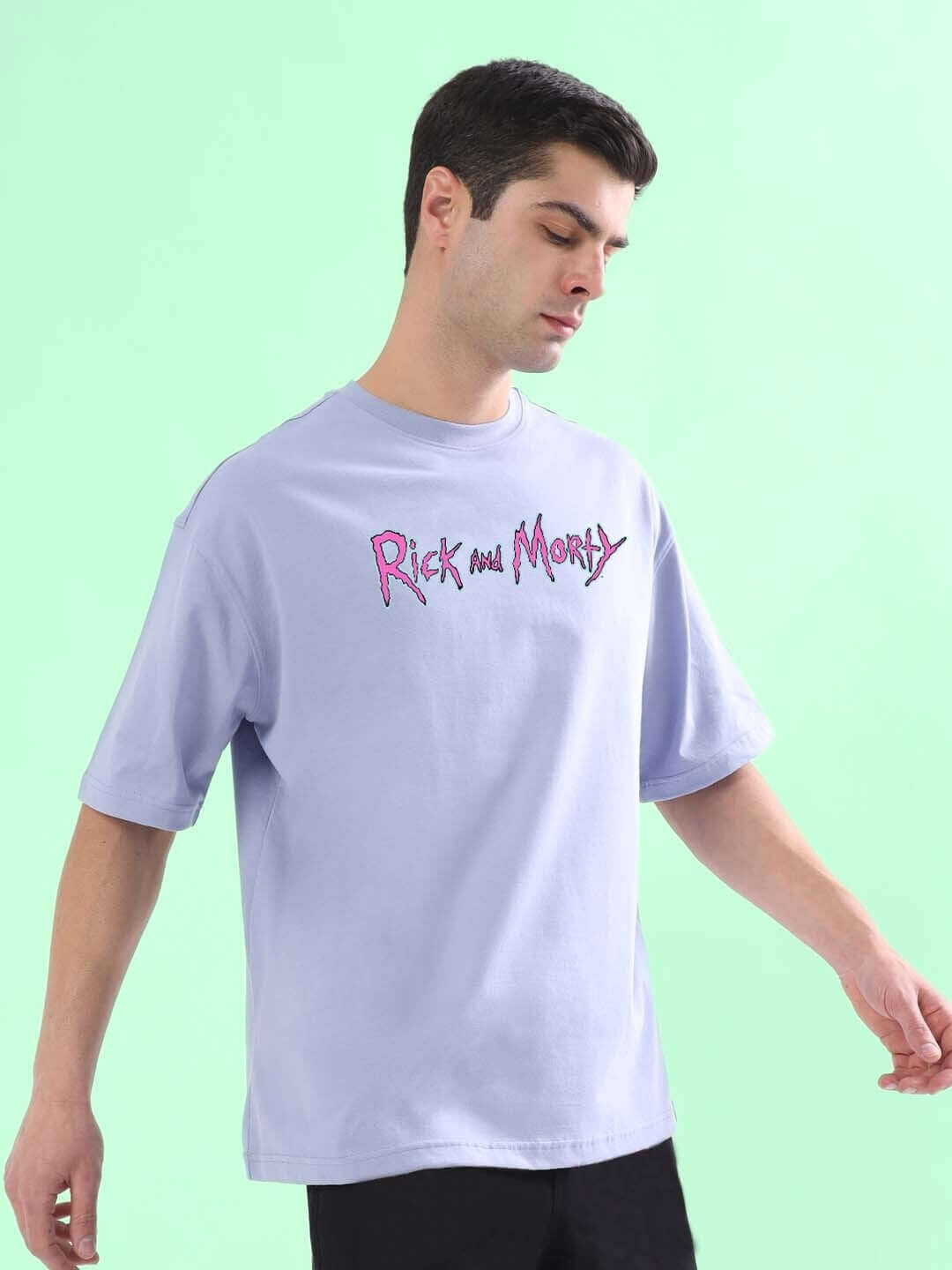 Man wearing a BACK IN TIME OVER-SIZED T-SHIRT LILAC with a graphic design on a mint green background.