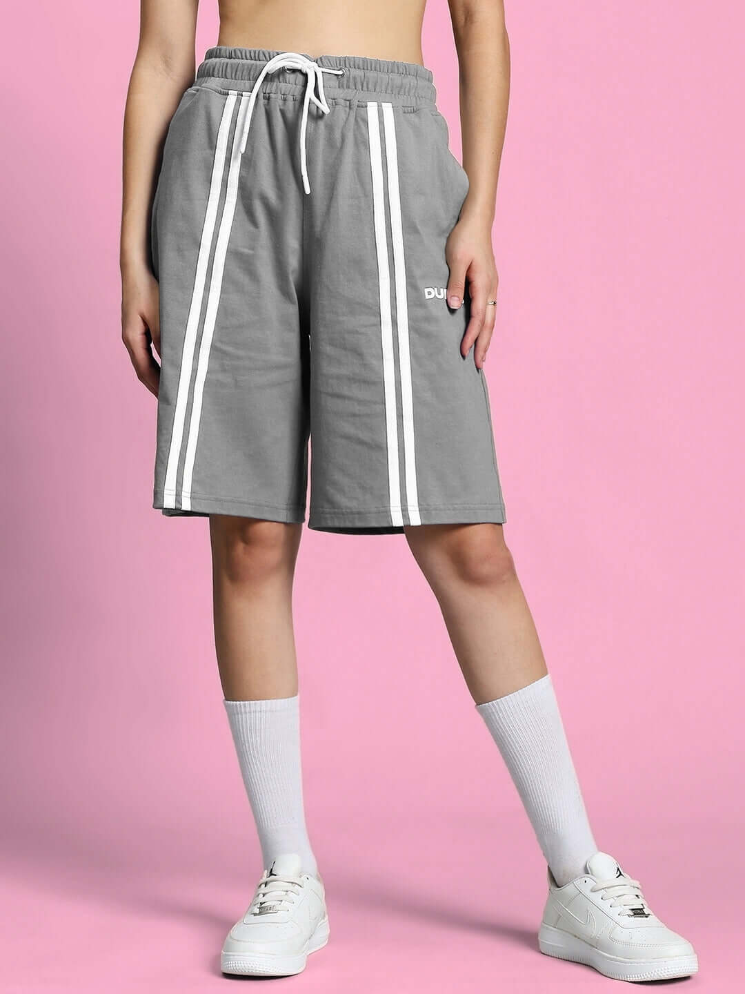 Women's grey regular fit shorts with white stripes, adjustable drawstring, and custom fit option by DUDS, worn by a model on a pink backdrop.