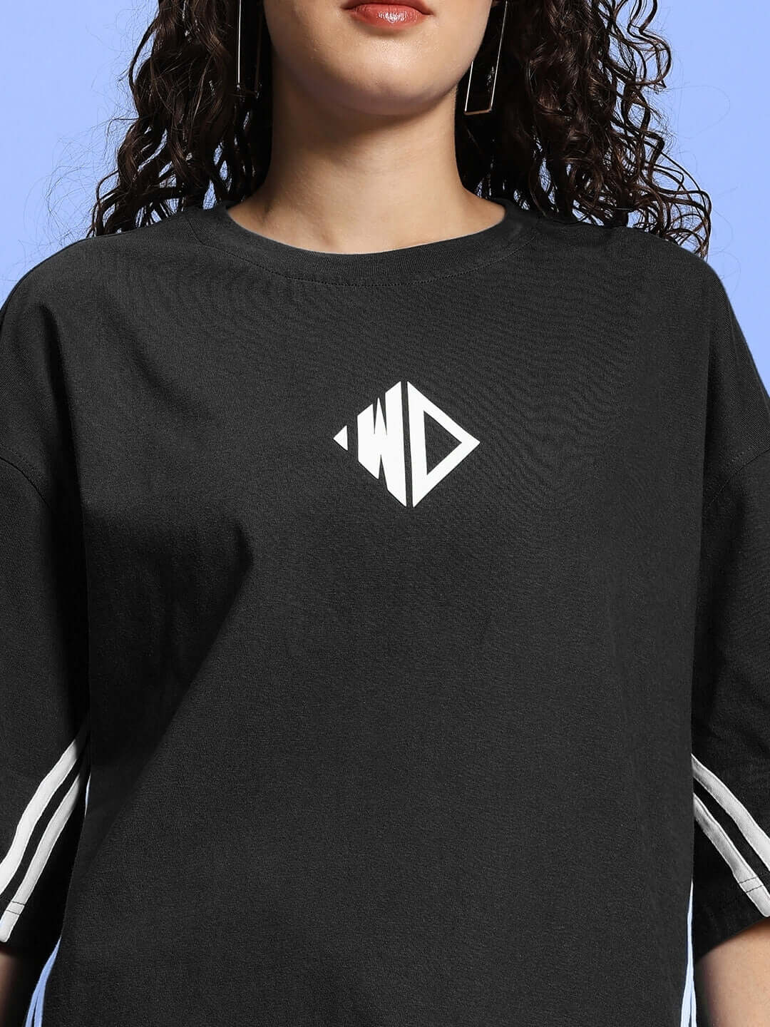 Woman wearing black oversized t-shirt with logo, made of premium cotton French terry, suitable for casual wear.