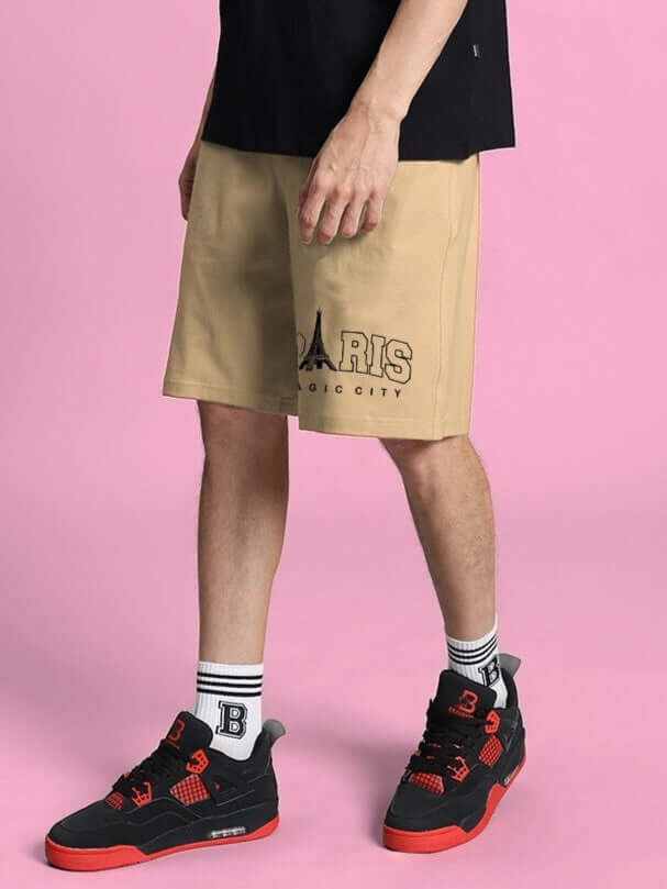 Model wearing MAGIC CITY beige summer shorts with custom fit option, featuring a Paris city design. Available for prepaid orders.