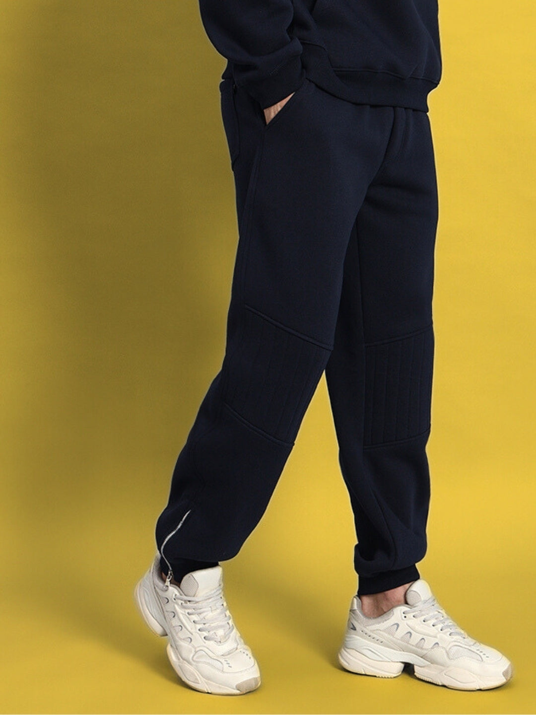 Navy blue Fight Night fleece joggers worn with white sneakers against a yellow background, showcasing casual athletic style.