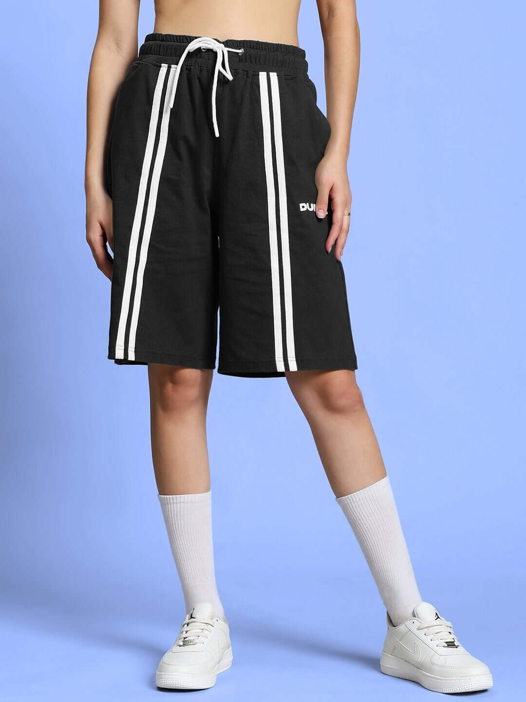 Model wearing women's black regular fit shorts with white stripes, showcasing trendy and customizable fashion option by DUDS.