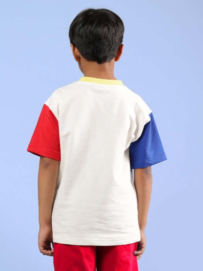 Child wearing off-white, shark fish printed oversized t-shirt with red and blue sleeves from DUDS, suitable for boys and girls.