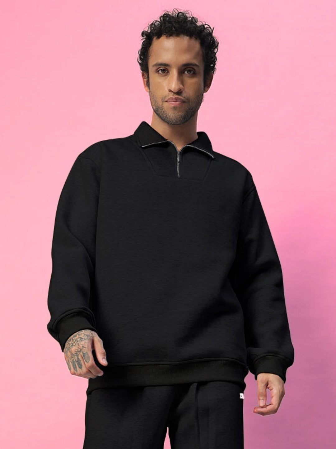 Model wearing Bona-Fide Cotton Fleece Co-ord in black, featuring a fleece-lined sweatshirt and joggers against a pink background.