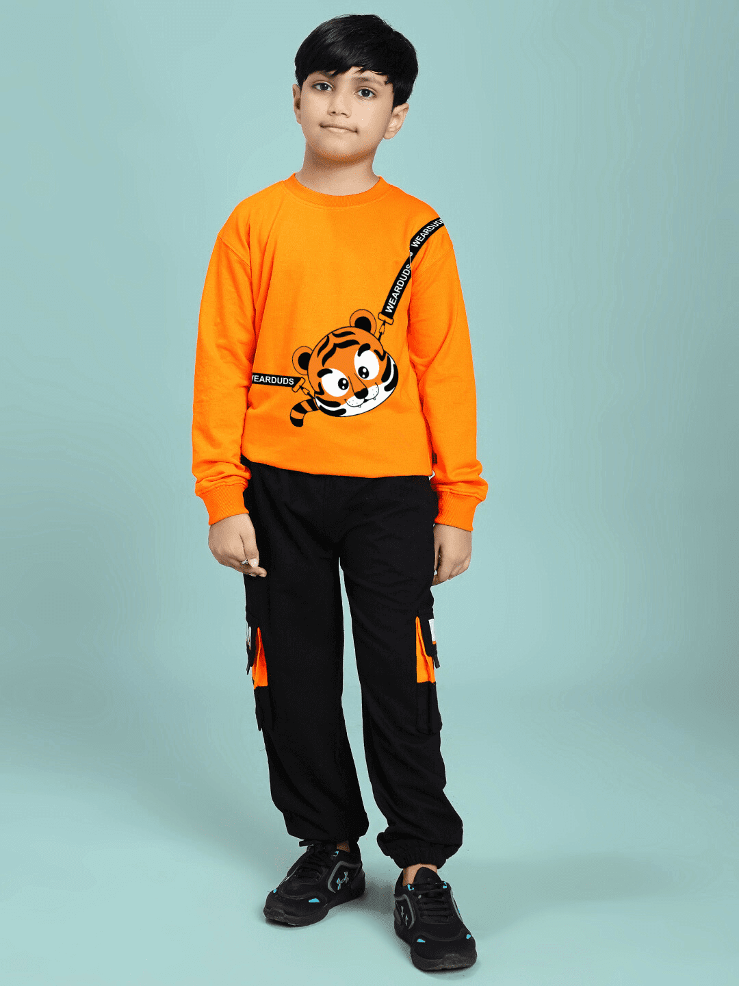 Boy wearing TIGON KIDS CO-ORD SET FOR BOYS AND GIRLS ORANGE BLACK, showcasing vibrant orange top and black pants with tiger print.